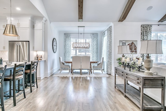 dining space with beam ceiling, light hardwood / wood-style flooring, and a wealth of natural light