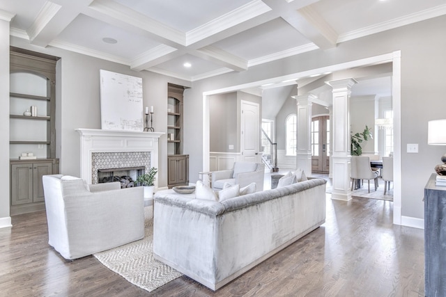 living room featuring hardwood / wood-style flooring, a fireplace, built in shelves, beamed ceiling, and ornate columns