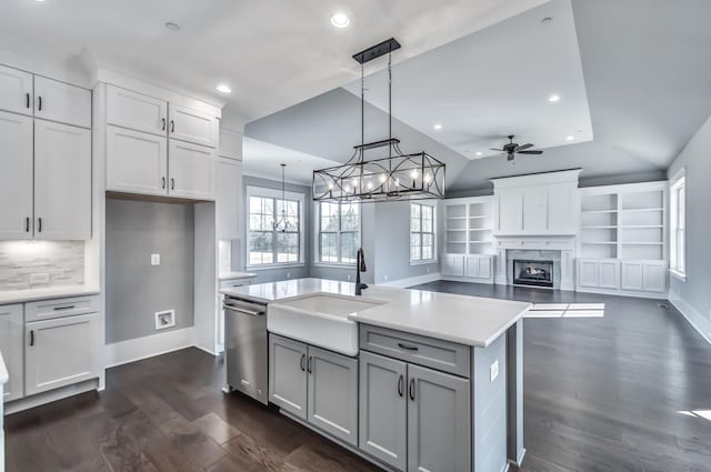 kitchen featuring an island with sink, white cabinetry, sink, hanging light fixtures, and stainless steel dishwasher