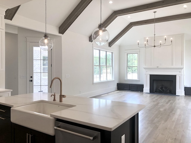 kitchen featuring hanging light fixtures, sink, dishwasher, and a center island with sink