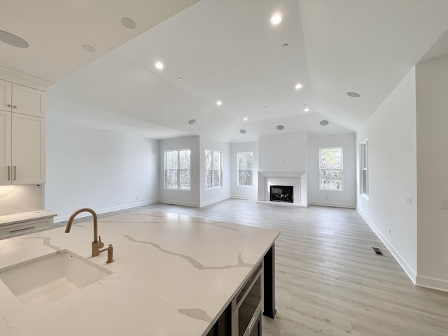 kitchen featuring white cabinetry, plenty of natural light, light stone countertops, and sink