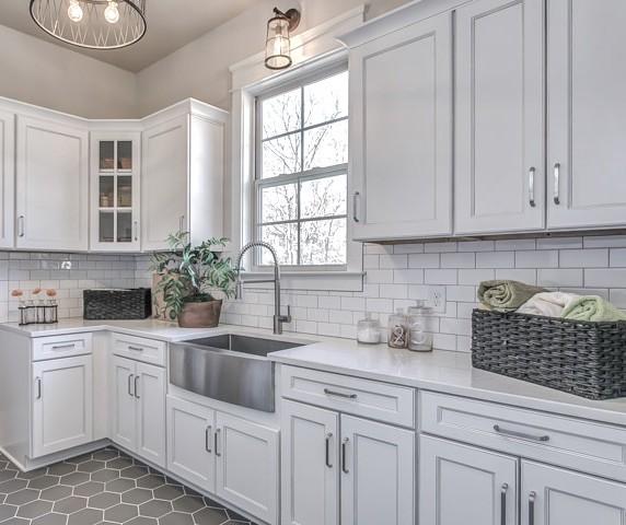 kitchen with tasteful backsplash, sink, and white cabinets