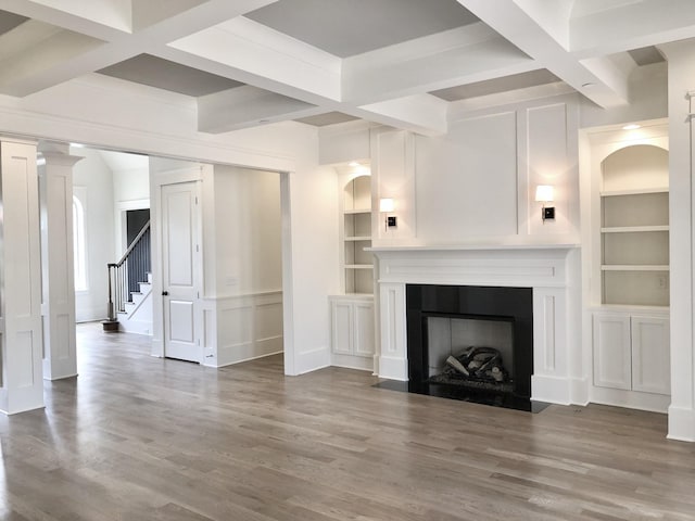 unfurnished living room featuring decorative columns, coffered ceiling, wood-type flooring, built in shelves, and beamed ceiling