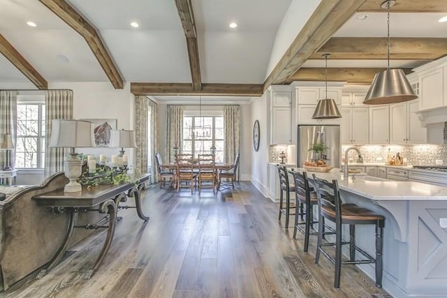 kitchen with pendant lighting, sink, stainless steel refrigerator, a breakfast bar, and dark hardwood / wood-style floors