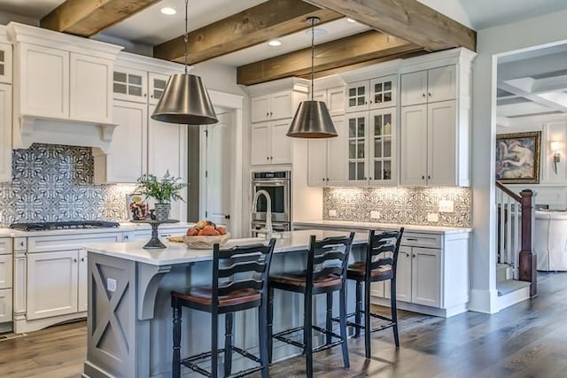 kitchen featuring white cabinetry, decorative light fixtures, and a center island with sink