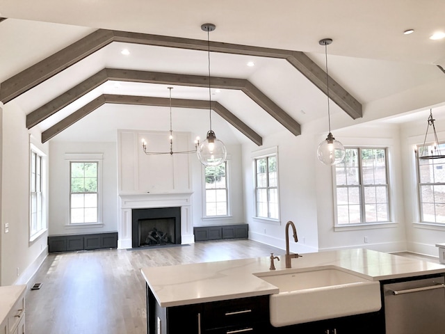 kitchen featuring hanging light fixtures, sink, a kitchen island with sink, and lofted ceiling with beams