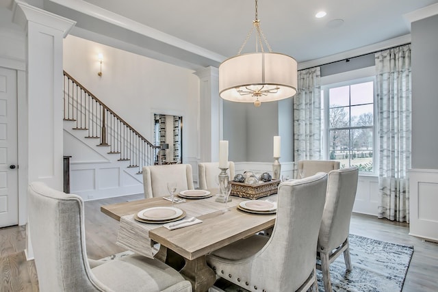 dining room featuring crown molding, light hardwood / wood-style floors, and ornate columns