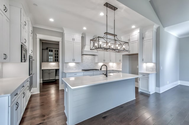 kitchen with a kitchen island with sink, hanging light fixtures, dark hardwood / wood-style floors, custom range hood, and white cabinets