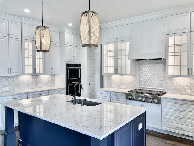 kitchen featuring pendant lighting, stainless steel gas stovetop, sink, and a center island with sink