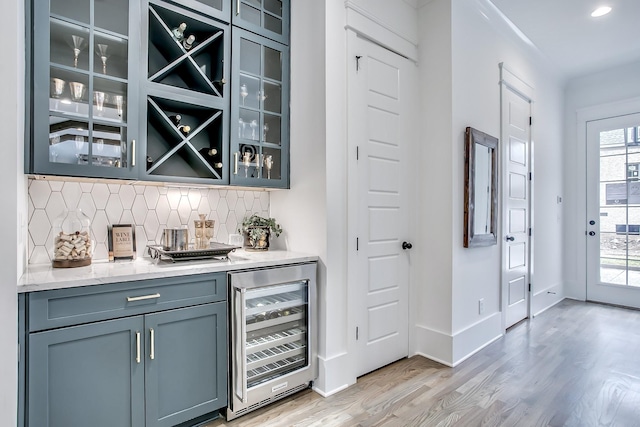 bar with a wealth of natural light, wine cooler, light hardwood / wood-style floors, and decorative backsplash