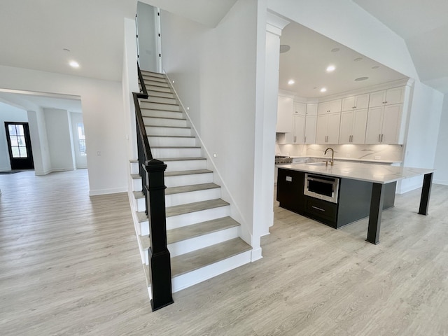 stairway with vaulted ceiling, sink, and hardwood / wood-style floors