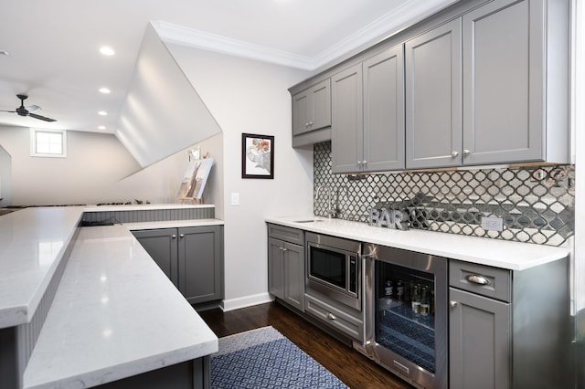 kitchen with dark wood-type flooring, stainless steel microwave, gray cabinets, kitchen peninsula, and beverage cooler