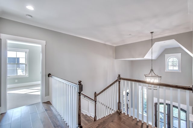 stairway with an inviting chandelier, hardwood / wood-style flooring, and vaulted ceiling