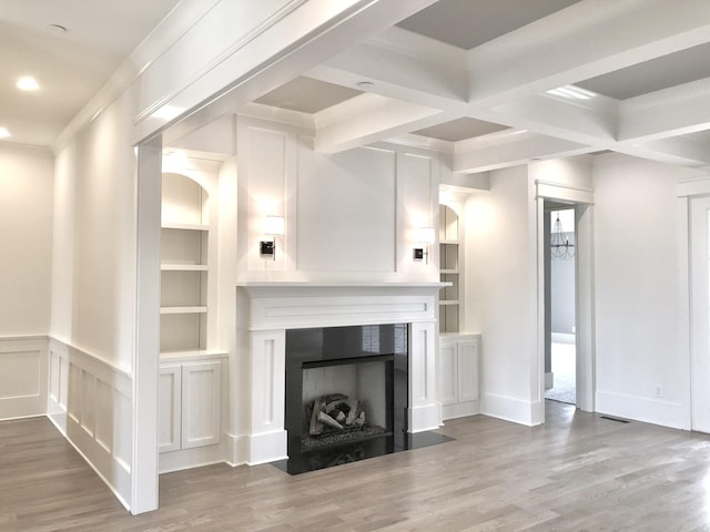 unfurnished living room featuring hardwood / wood-style flooring, coffered ceiling, beam ceiling, and built in shelves