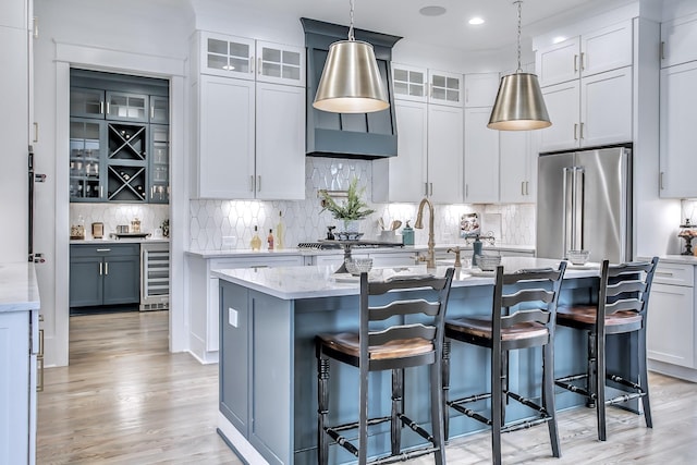 kitchen featuring stainless steel appliances, an island with sink, pendant lighting, and wine cooler