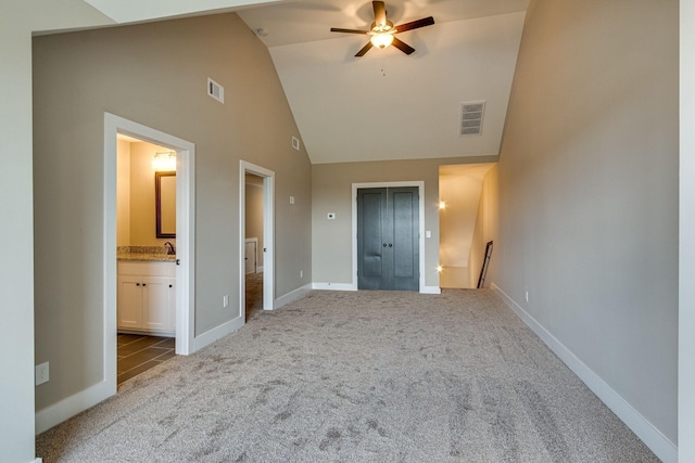 unfurnished bedroom featuring lofted ceiling, connected bathroom, light colored carpet, and ceiling fan