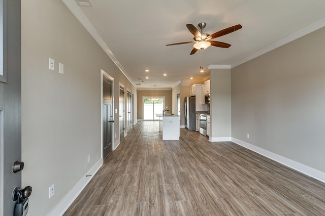 unfurnished living room featuring sink, crown molding, ceiling fan, and light wood-type flooring