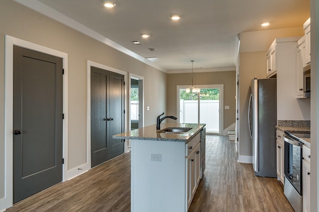 kitchen with sink, white cabinetry, decorative light fixtures, appliances with stainless steel finishes, and a kitchen island with sink