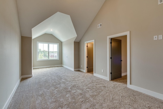 additional living space featuring light carpet and vaulted ceiling