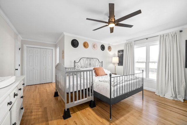 bedroom with ceiling fan, ornamental molding, a closet, and light hardwood / wood-style flooring