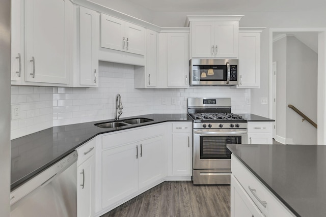 kitchen with dark wood-type flooring, sink, appliances with stainless steel finishes, white cabinets, and backsplash