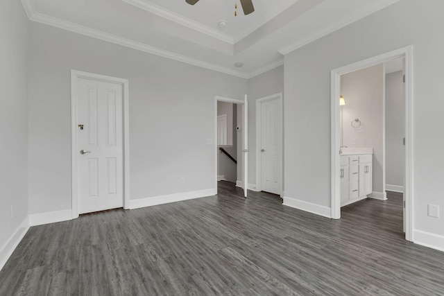 unfurnished bedroom featuring a raised ceiling, dark wood-type flooring, connected bathroom, and ceiling fan