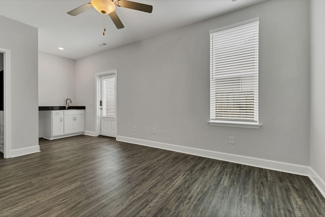 unfurnished living room with ceiling fan, dark hardwood / wood-style flooring, and sink