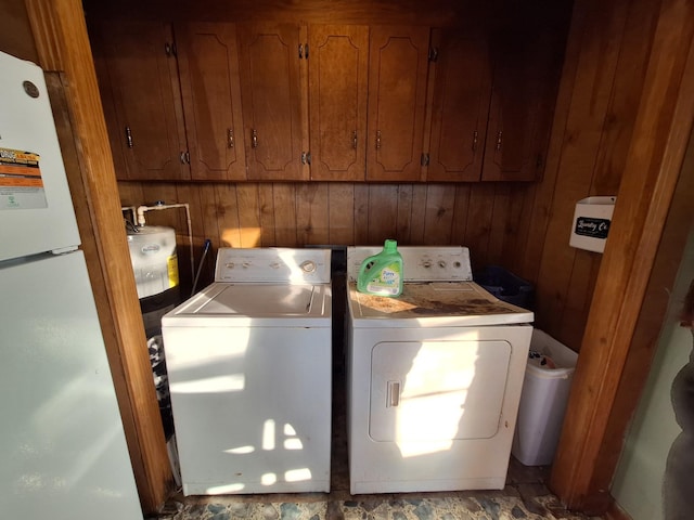 laundry room with wooden walls, cabinets, and washing machine and clothes dryer