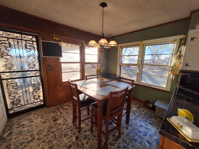 dining room with crown molding, a chandelier, and wood walls