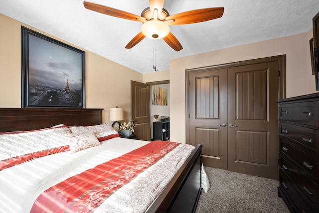 bedroom featuring ceiling fan, a closet, a textured ceiling, and dark colored carpet