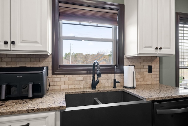 kitchen featuring tasteful backsplash, sink, light stone countertops, and white cabinets