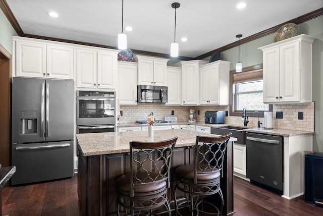 kitchen featuring white cabinetry, stainless steel appliances, a center island, light stone counters, and decorative light fixtures