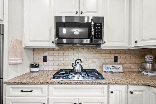 kitchen with white cabinetry, appliances with stainless steel finishes, light stone countertops, and tasteful backsplash