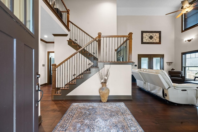 foyer with ornamental molding, dark hardwood / wood-style floors, ceiling fan, and a towering ceiling