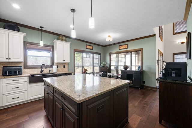 kitchen with a center island, sink, white cabinets, and decorative light fixtures