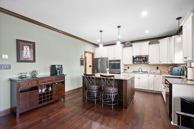 kitchen featuring sink, light stone counters, appliances with stainless steel finishes, a kitchen island, and pendant lighting