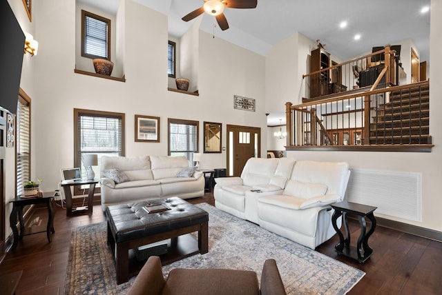 living room featuring dark hardwood / wood-style floors, ceiling fan, and a high ceiling