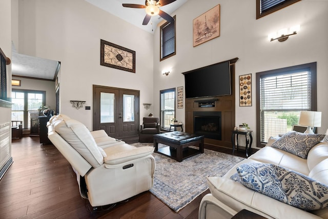 living room featuring dark hardwood / wood-style flooring, ceiling fan, and a high ceiling