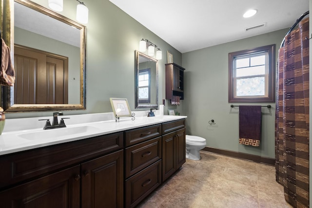 bathroom with a healthy amount of sunlight, toilet, and vanity