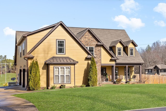 craftsman inspired home with a porch, a garage, a front yard, and central air condition unit