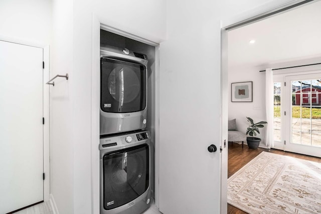 washroom featuring hardwood / wood-style flooring and stacked washing maching and dryer