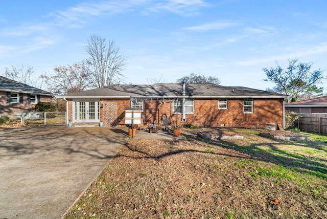 rear view of house with french doors, a patio, and a lawn