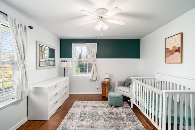 bedroom featuring ceiling fan, dark hardwood / wood-style flooring, and a crib