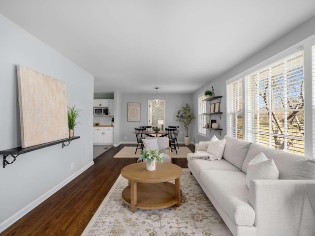 living room with baseboards and dark wood-style flooring