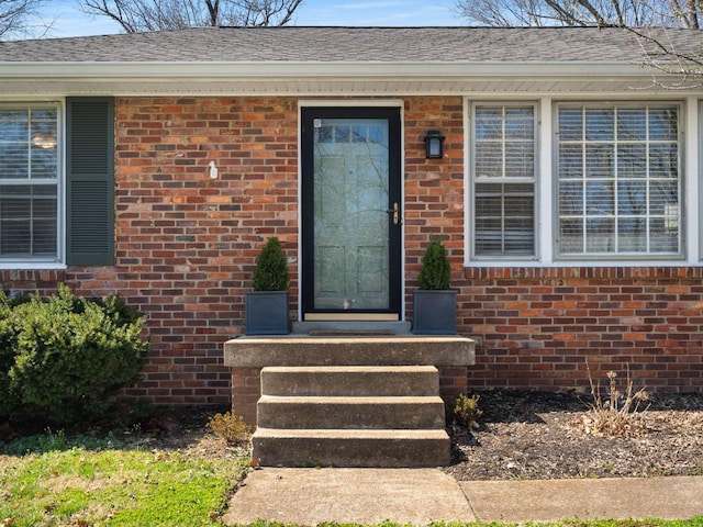 property entrance featuring brick siding and roof with shingles