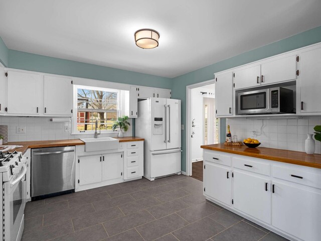 kitchen with a sink, butcher block countertops, white cabinetry, and stainless steel appliances