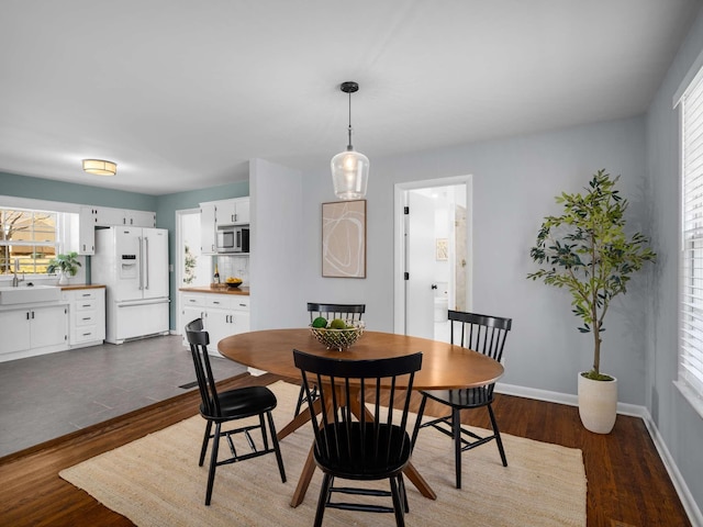 dining area with baseboards and dark wood-style flooring