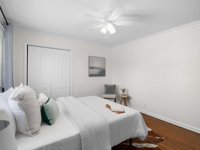 bedroom with a ceiling fan, wood finished floors, a closet, crown molding, and baseboards