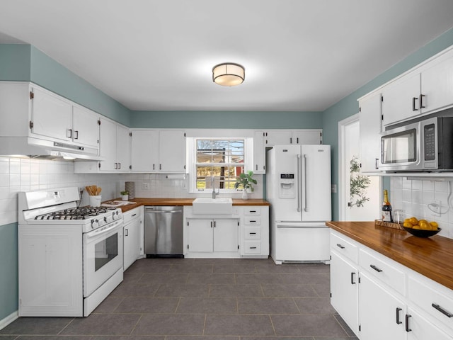 kitchen with under cabinet range hood, a sink, white cabinetry, stainless steel appliances, and butcher block counters