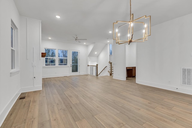 unfurnished living room with ceiling fan with notable chandelier and light hardwood / wood-style flooring